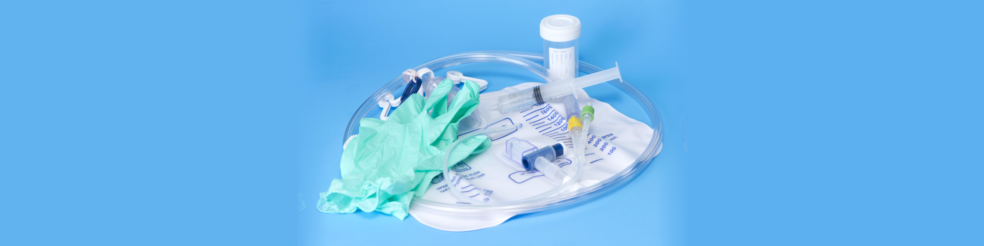 Foley catheter and drainage bag with sterile gloves and specimen container on blue background