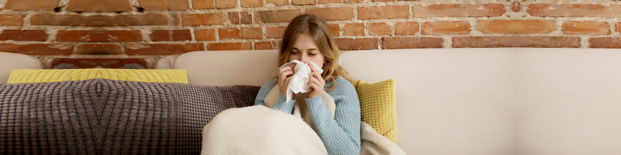 Young ill woman sitting on sofa, she is having cold or flu
